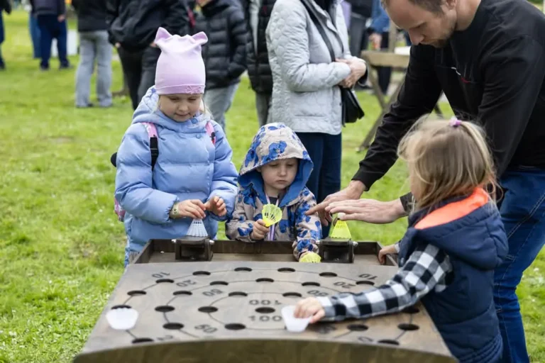 Vaikai ir tėvai žaidžia lauko žaidimus bendruomenės šventėje