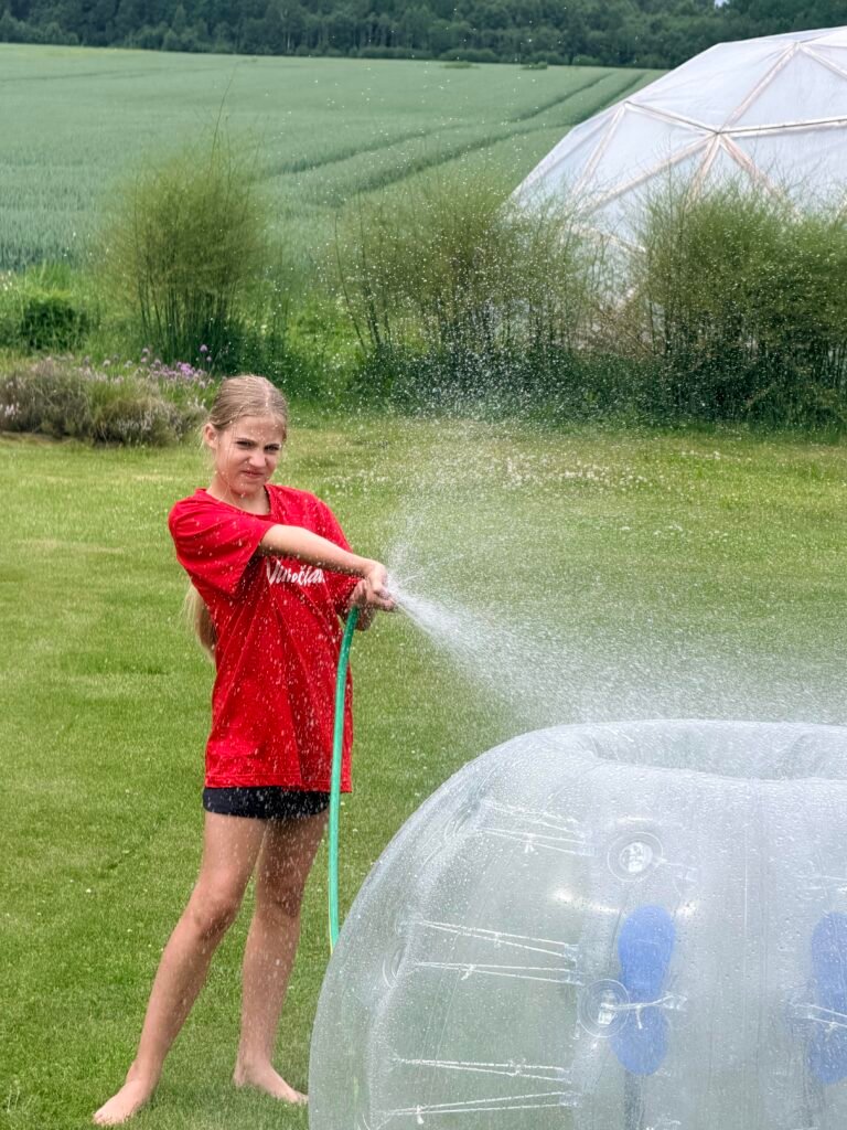 Mergaitė žarna plauna burbulų futbolo kamuolį pievoje